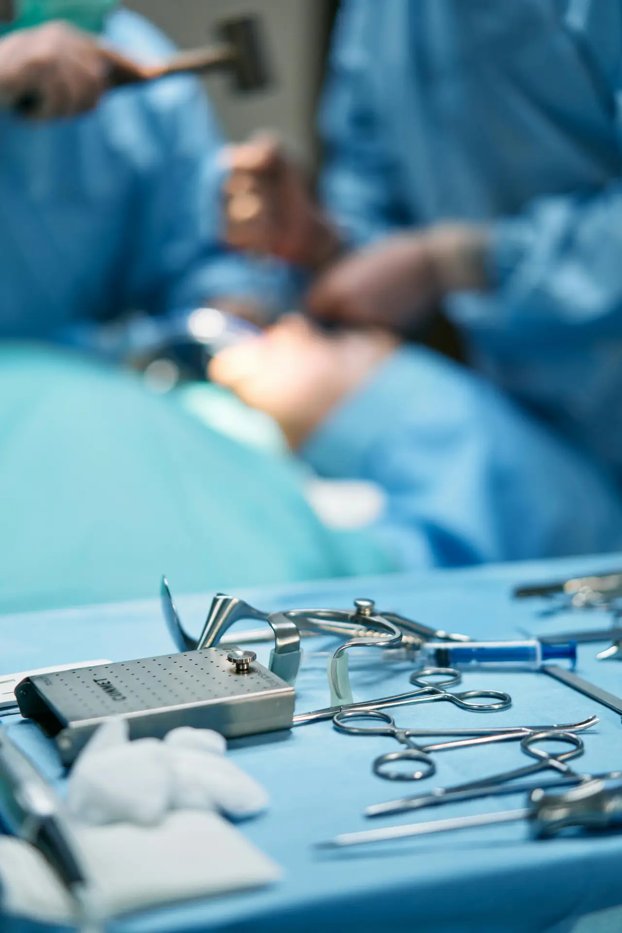 Home Close-up of surgical tools with surgeons in the background in an operating room.